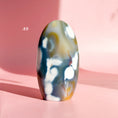 Load image into Gallery viewer, Brown and black agate freeform with clusters of white inclusions on a pink background.