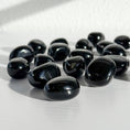 Load image into Gallery viewer, Group of black obsidian tumbles lay scattered in the center of the image on a white background.