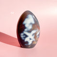 Load image into Gallery viewer, Dark grey agate freeform with groups of white inclusions set on a soft pink background.