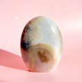 Load image into Gallery viewer, Pale grey and brown agate freeform with black speckles throughout, set on a pink background.