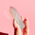 Load image into Gallery viewer, Hand holds pale white agate point on a soft pink background.