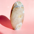 Load image into Gallery viewer, Light brown agate freeform with quartz-like inclusions on a soft pink background.