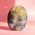 Load image into Gallery viewer, Grey and brown agate freeform with orange inclusions and large black speckles throughout set on a pale pink background. 
