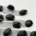 Load image into Gallery viewer, Group of black obsidian tumbles lay scattered in the center of the image on a white background. 
