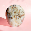 Load image into Gallery viewer, White agate freeform with pale brown spots throughout the stone set on a pink background. 
