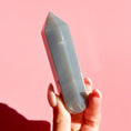 Load image into Gallery viewer, Hand holds grey agate point on a soft pink background. 
