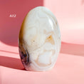 Load image into Gallery viewer, White agate freeform with light brown and black glitter speckles set on a soft pink background. 
