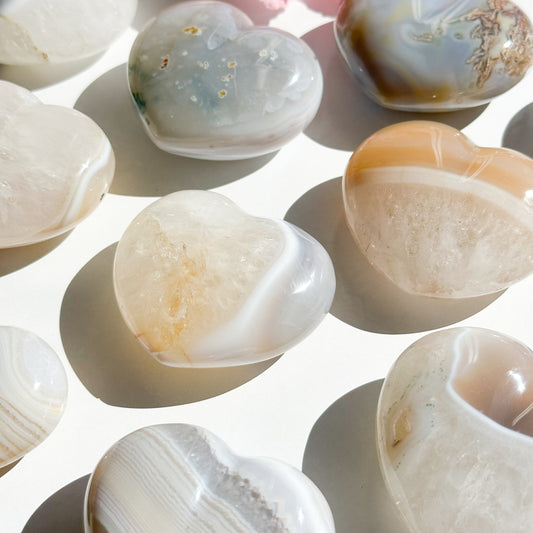 Nine agate hearts with quartz inclusions lay scattered on a white background. 